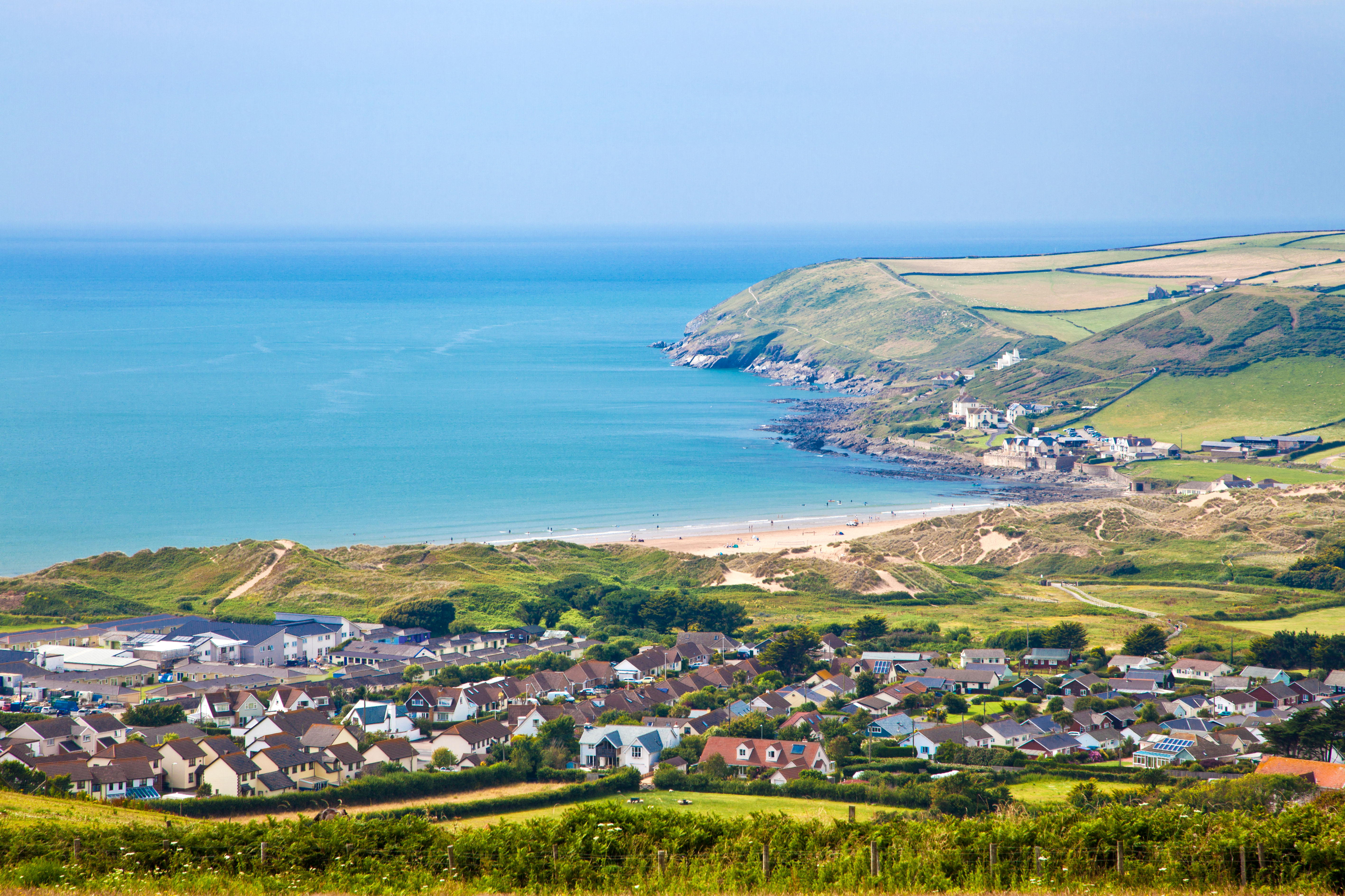 A clear view of a village from above and bay across mountains and out to the ocean