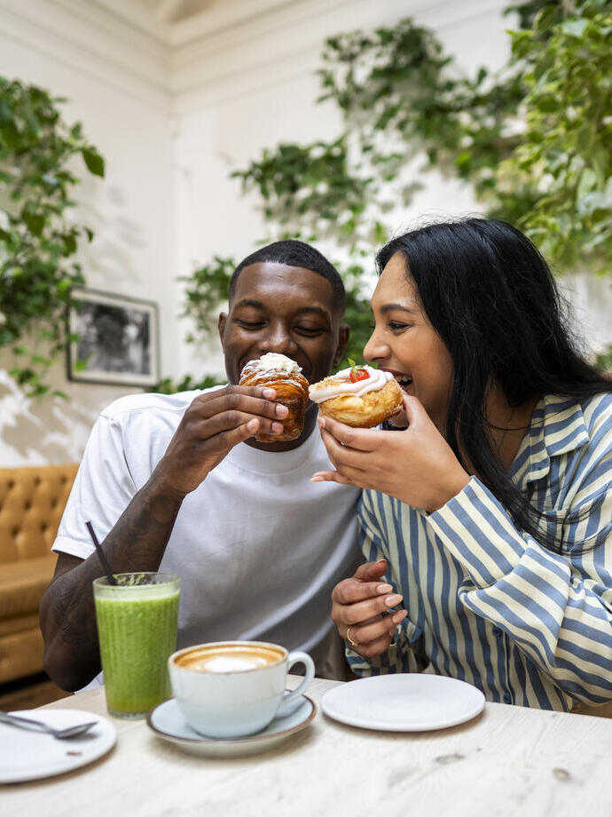 A man and a woman have cake and drinks in a cafe