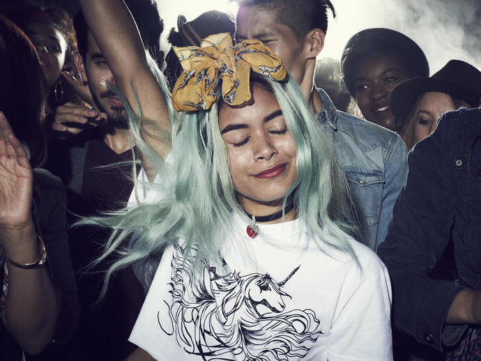 Girl with dyed hair, smiling, dancing with a group of people