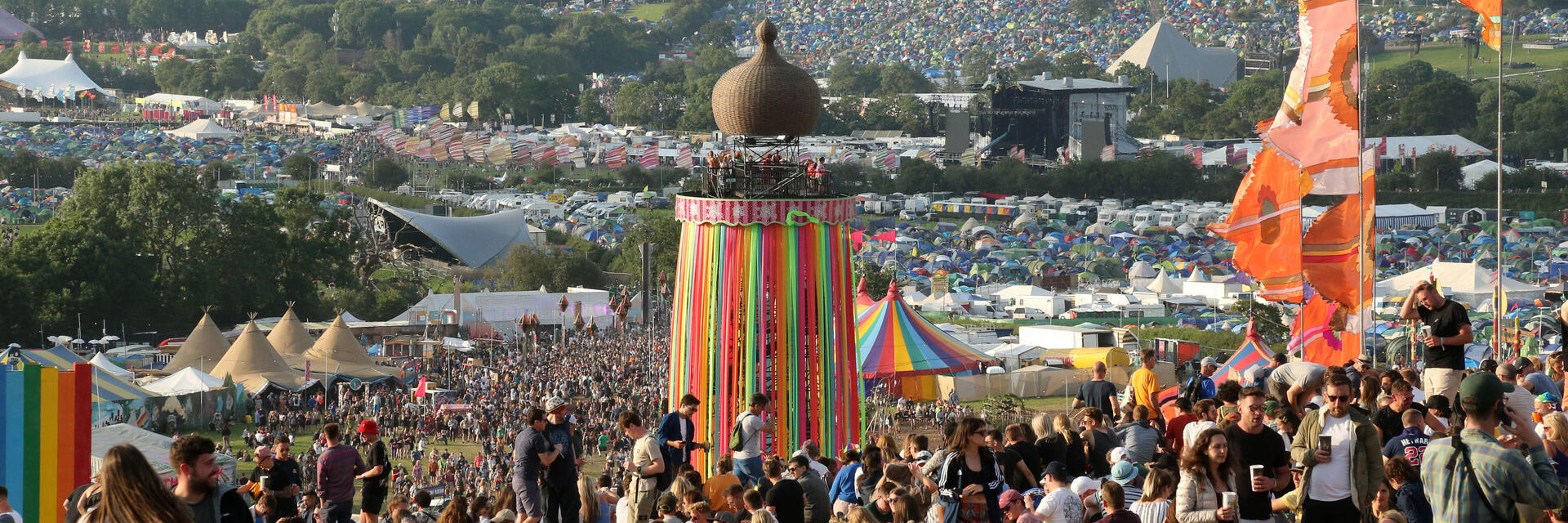 Crowd at Glastonbury Festival sitting on a hill during the day