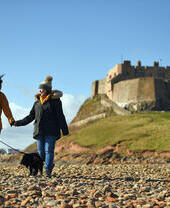 Visitors walking with their dog at Lindisfarne Castle, Northumberland