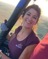 Una donna sorridente in una mongolfiera con i campi sottostanti