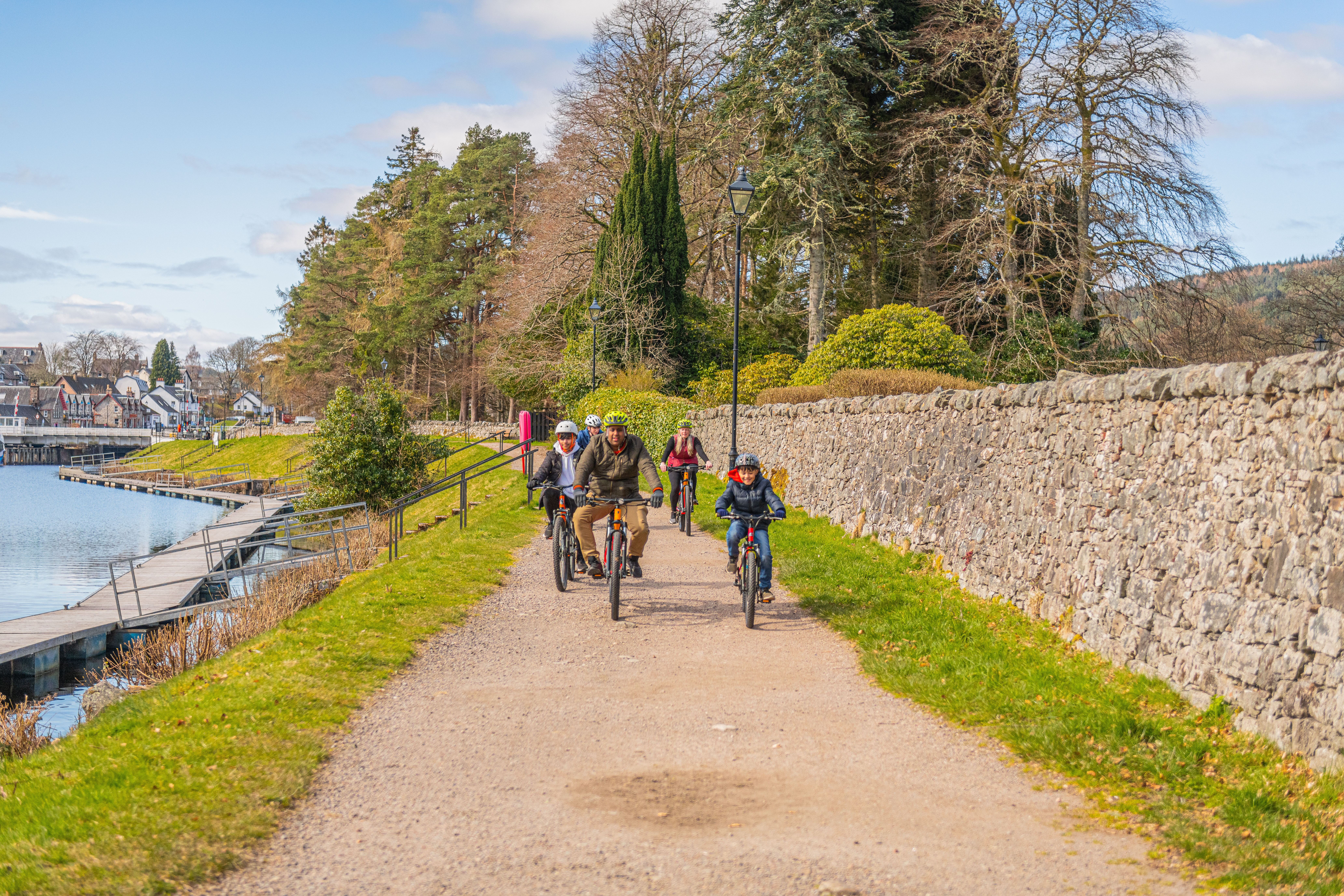 A family with three boys cycles along a canal towpath.