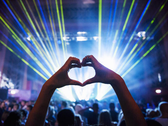 Woman making heart shape with hands at a music event