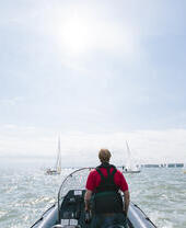 Man steering a power boat during a sailing race with yachts either side