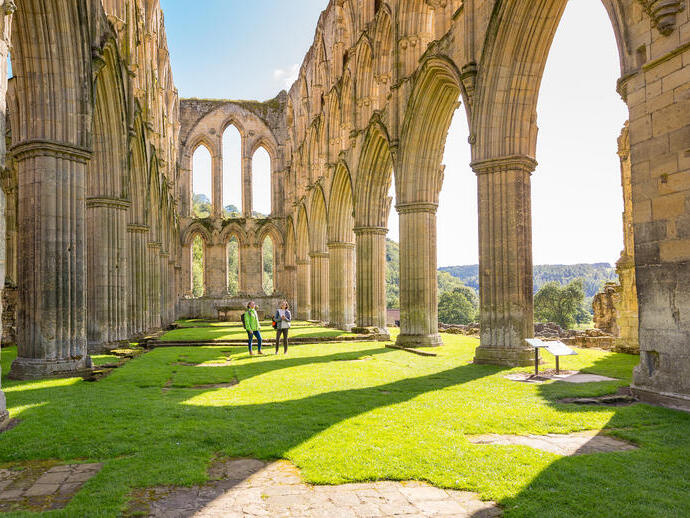 Two female friends in the central nave of a ruined abbey in the sunshine