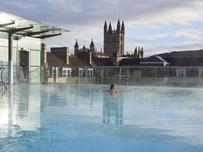Woman in a roof top swimming pool at a spa
