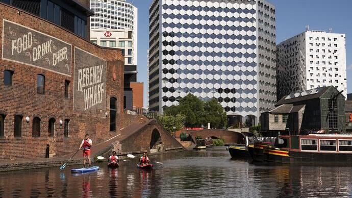 A group of people paddleboarding past the Regency Wharf