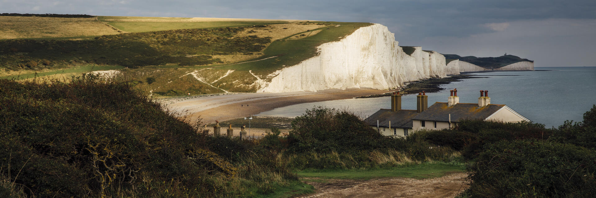 Ferienhäuser an der Küste mit Meer und weißen Klippen im Hintergrund