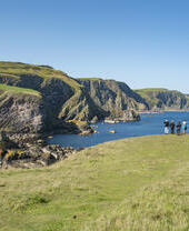 Grupo de personas en un acantilado contemplando una bahía