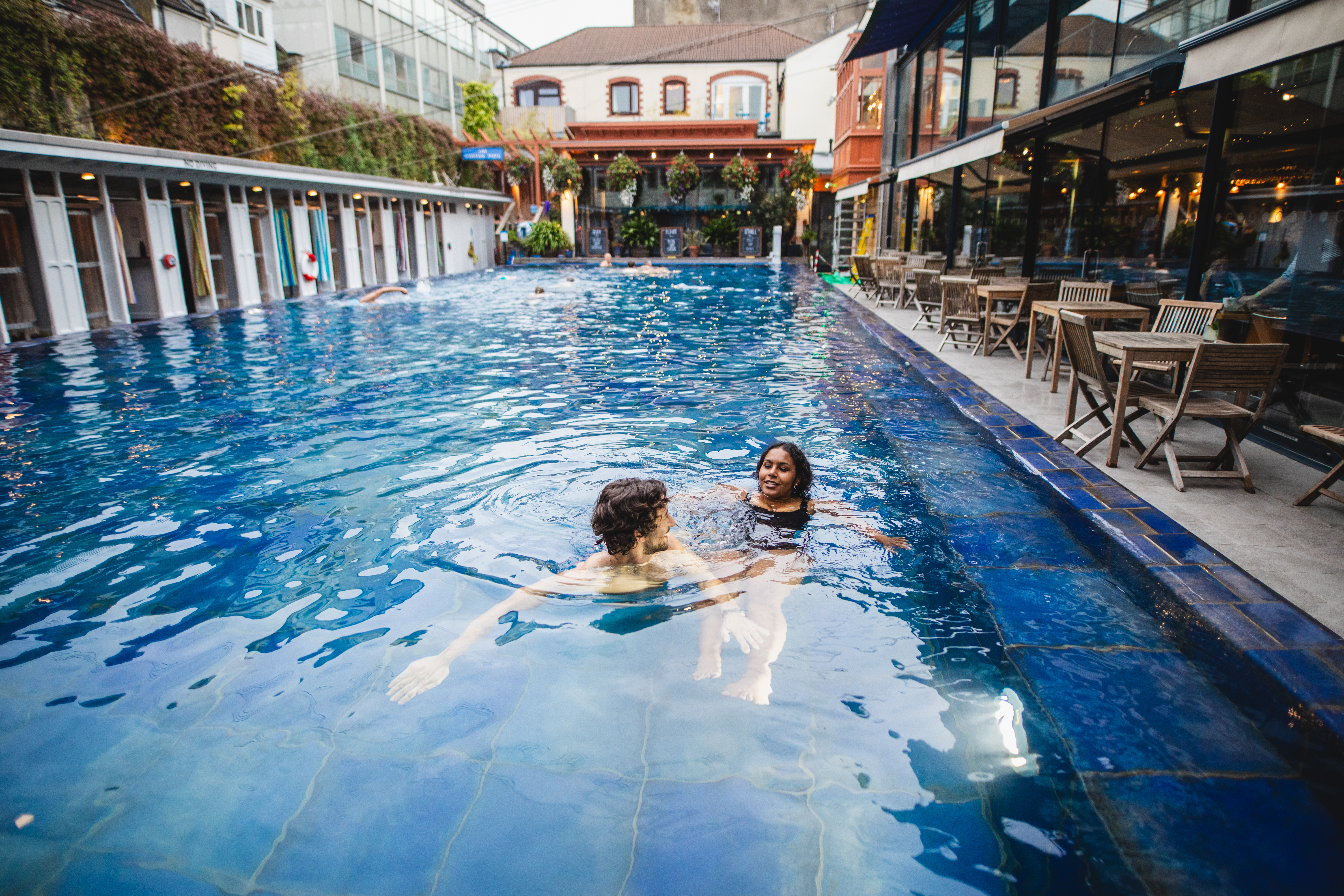 Man and woman enjoy a swim in an outdoor swimming pool
