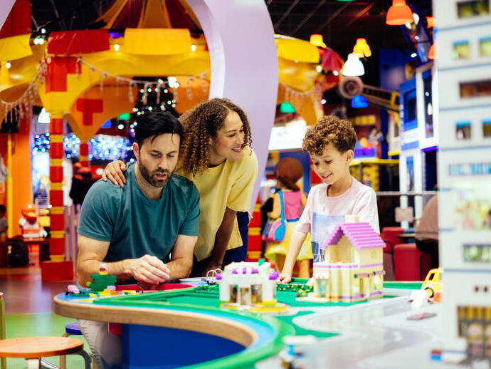 Mother, father and son laughing whilst playing with Lego