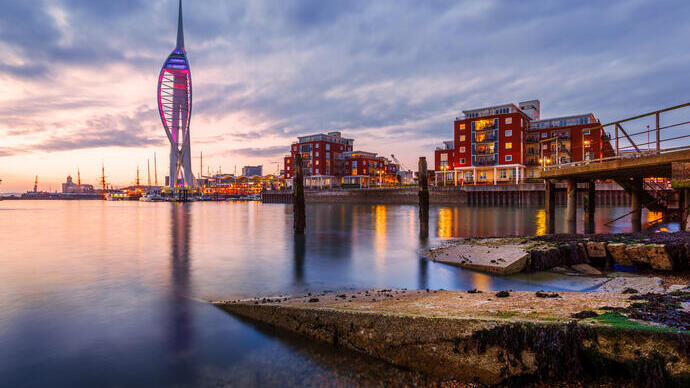 Hafen mit beleuchtetem Turm in der Abenddämmerung