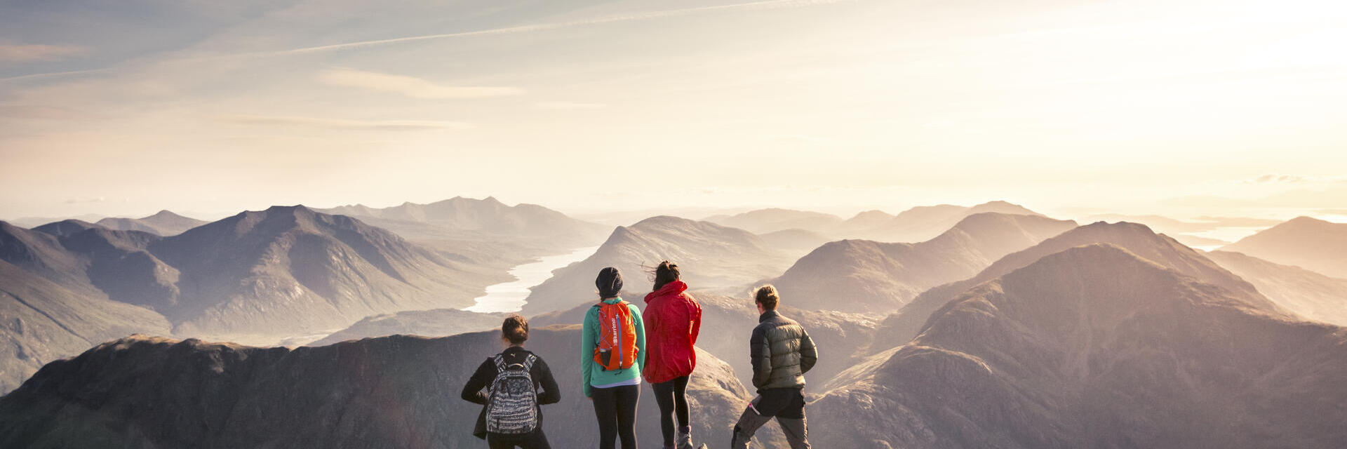 Un gruppo di persone in piedi su un punto elevato che ammira la vista sulle montagne sottostanti