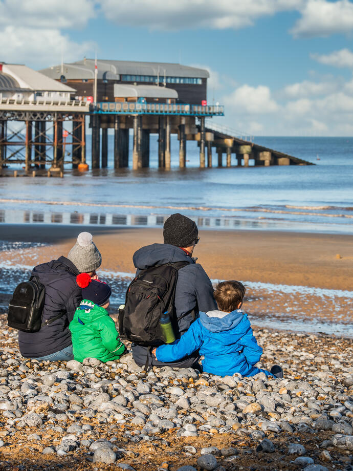 A family sitting on Cromer Beach looking out at the sea