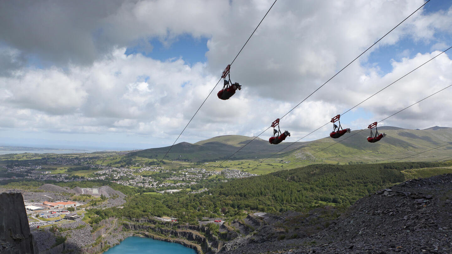 أشخاص يتزلجون على حبل عبر محجر كبير.