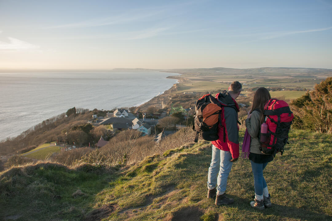 Couple with hiking equipment looking out over the cliffs towards the sea
