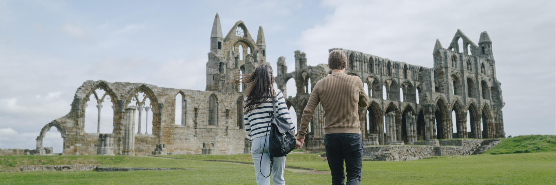 A man and woman walking towards a heritage Abbey building