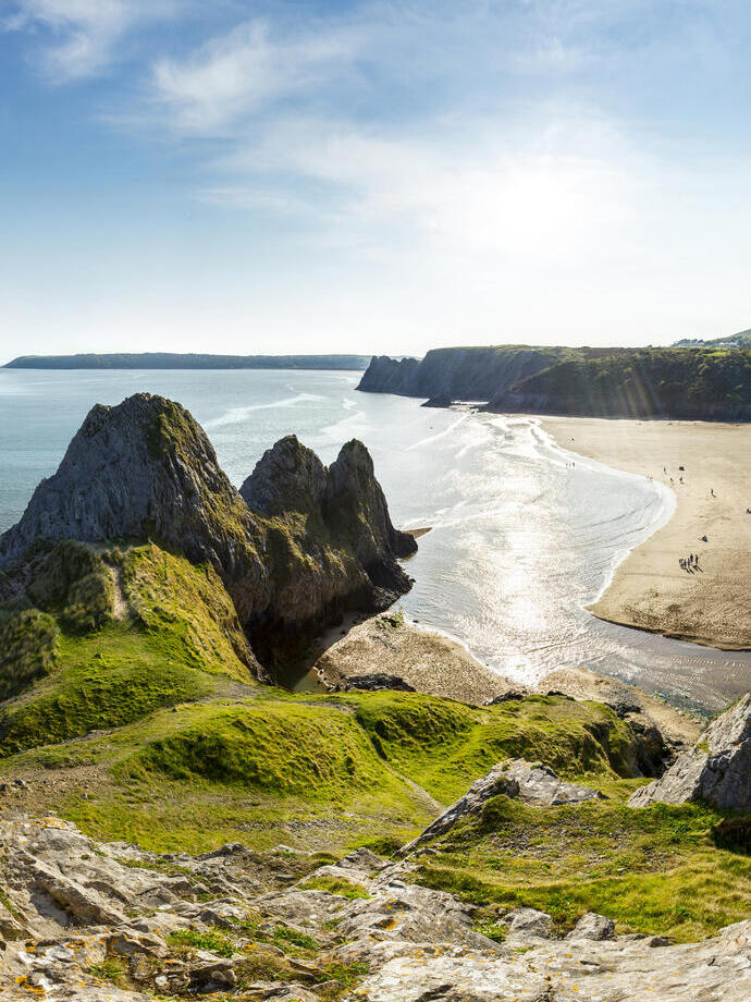 Côte avec une plage de sable et une péninsule rocheuse.