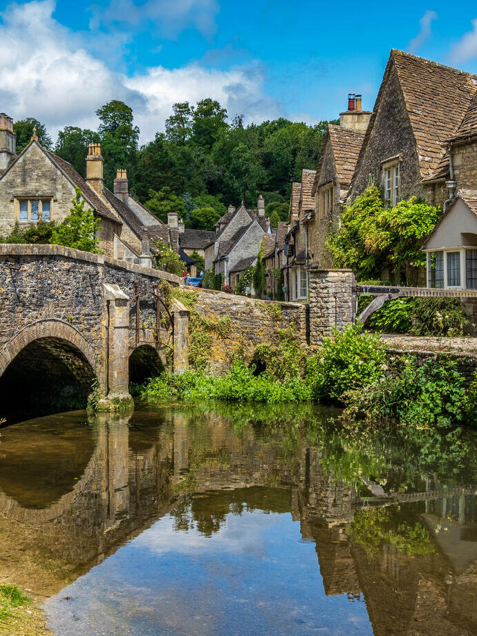 Cielo azul y reflejos en el pintoresco pueblo de Castle Combe, en los Cotswolds.