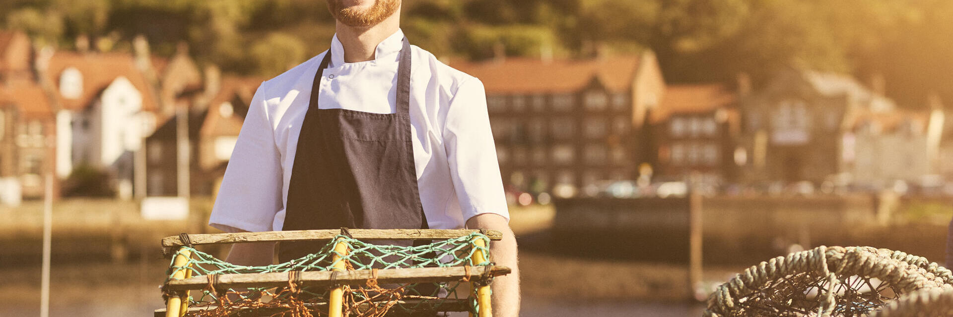 Homme tenant un casier à homards sur un quai au soleil