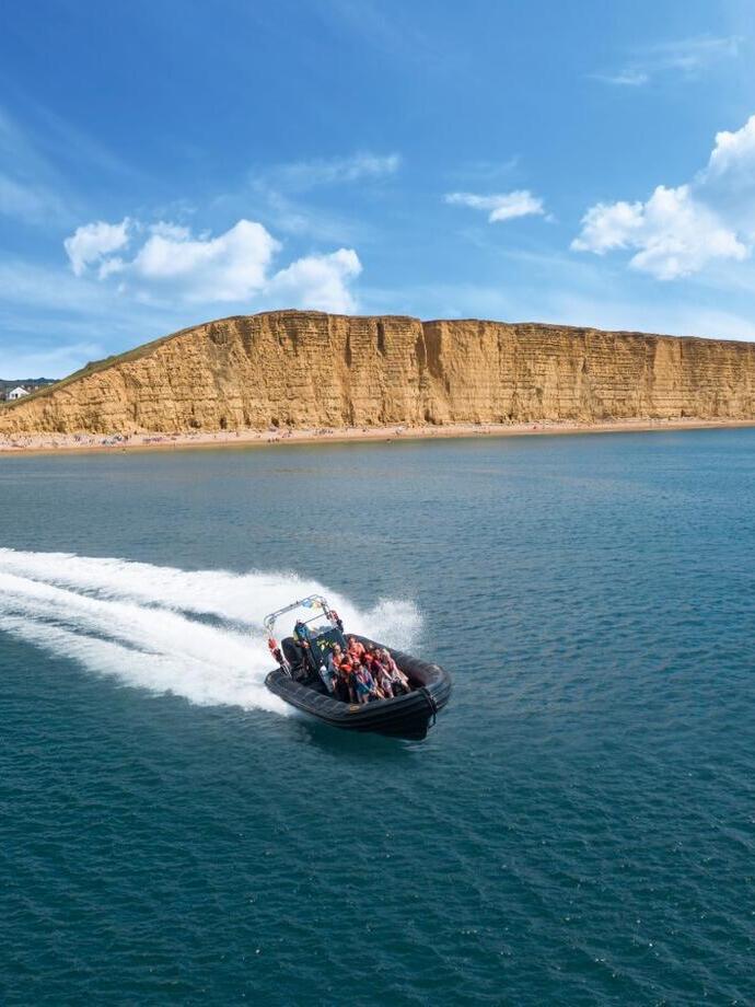 A speedboat carrying a group speeding through the ocean of Lyme Bay