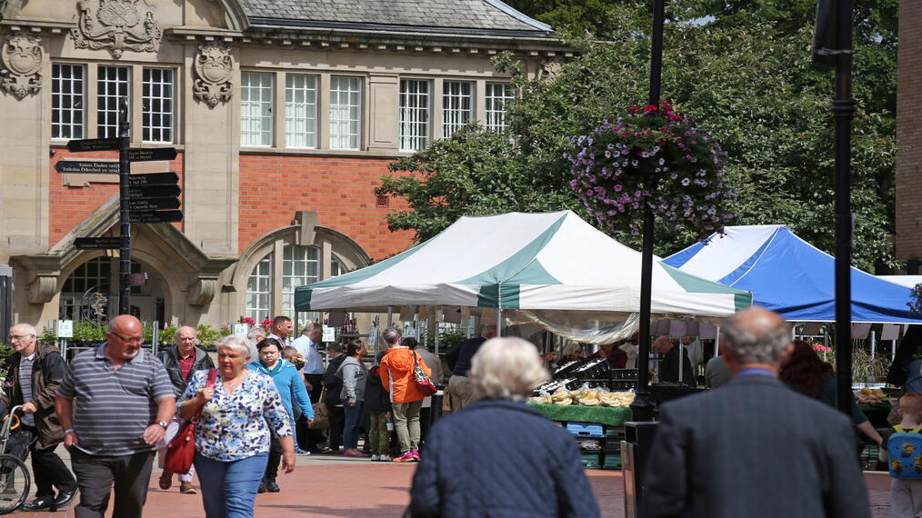 People visiting an outoor produce market near a historic building.