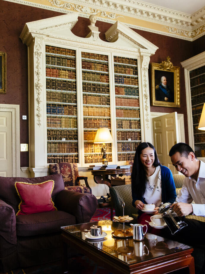 An asian couple, sitting on a sofa, having afternoon tea