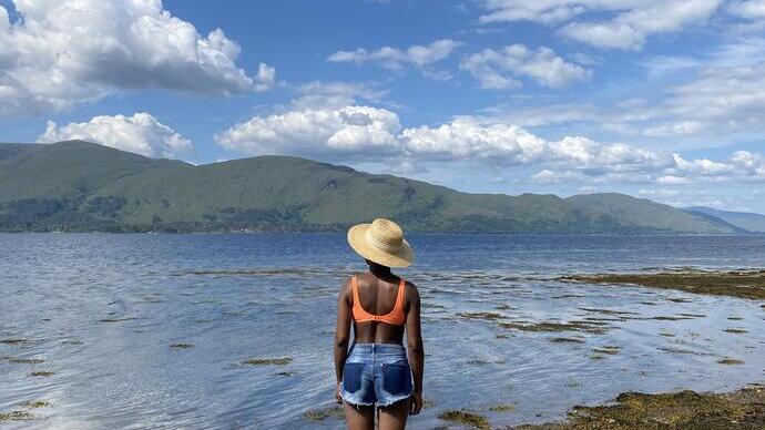 Woman stands on a rock looking over a lake