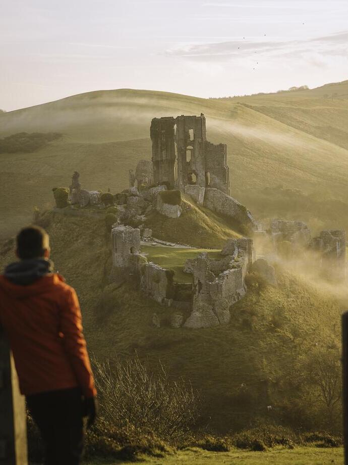 Man leaning on gatepost, looking out to views of castle