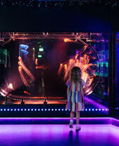 A girl stands looking at a tank with jellyfish