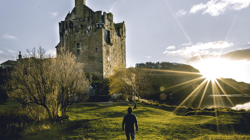 Man walking towards a castle at sunrise