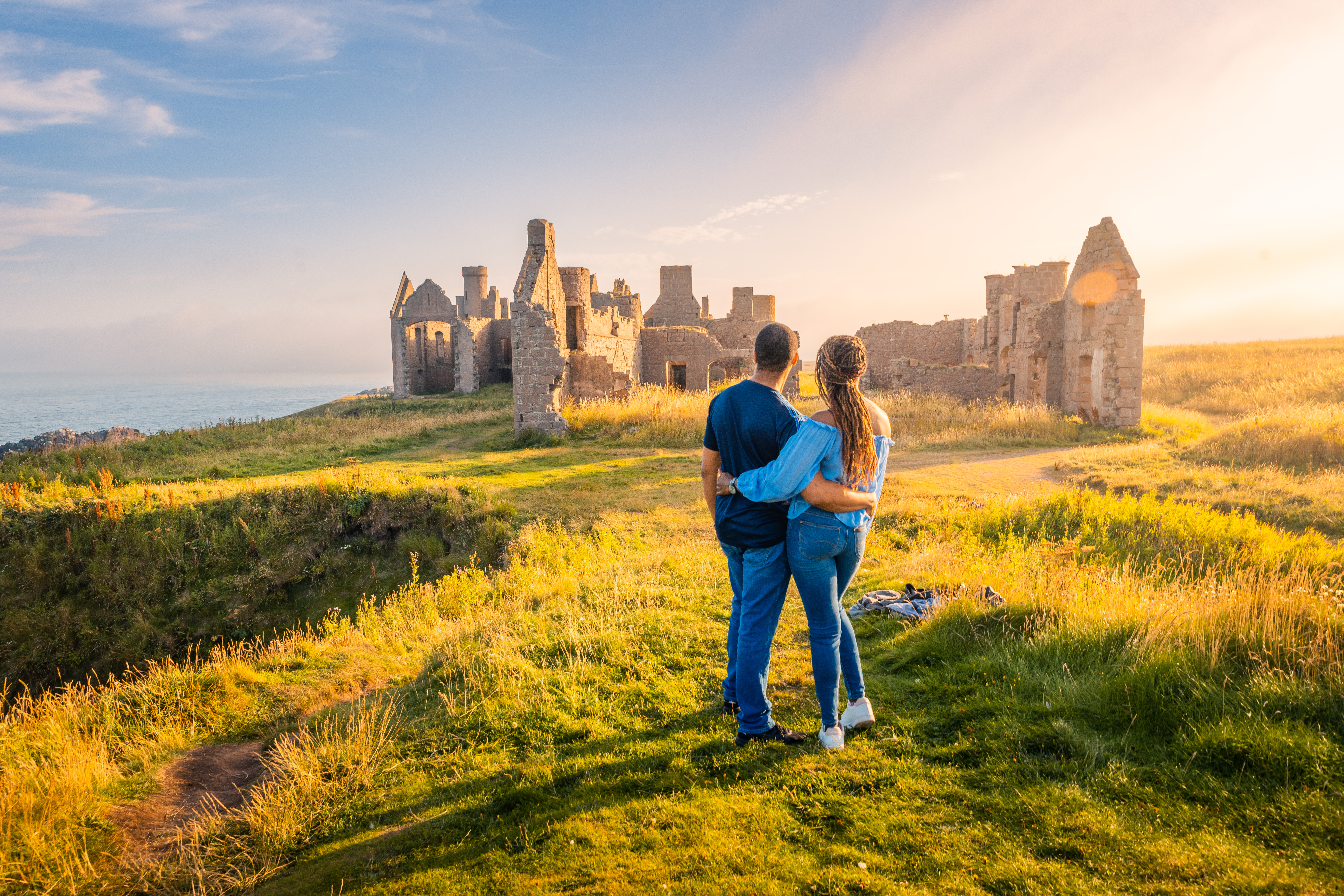Una pareja disfrutando de las vistas de las ruinas de un castillo a la hora dorada.