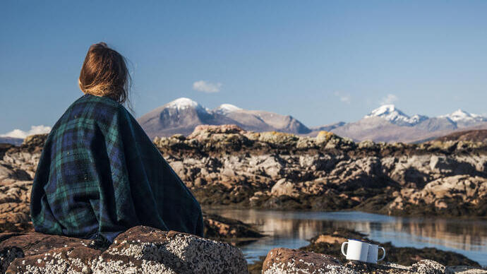 Woman sitting on a rock looking at the mountains in the distance