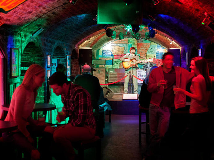 Homme sur scène jouant de la guitare dans un club au plafond voûté