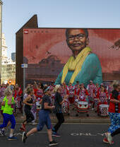 Des gens courent devant un groupe de percussionnistes et des œuvres d'art urbain colorées