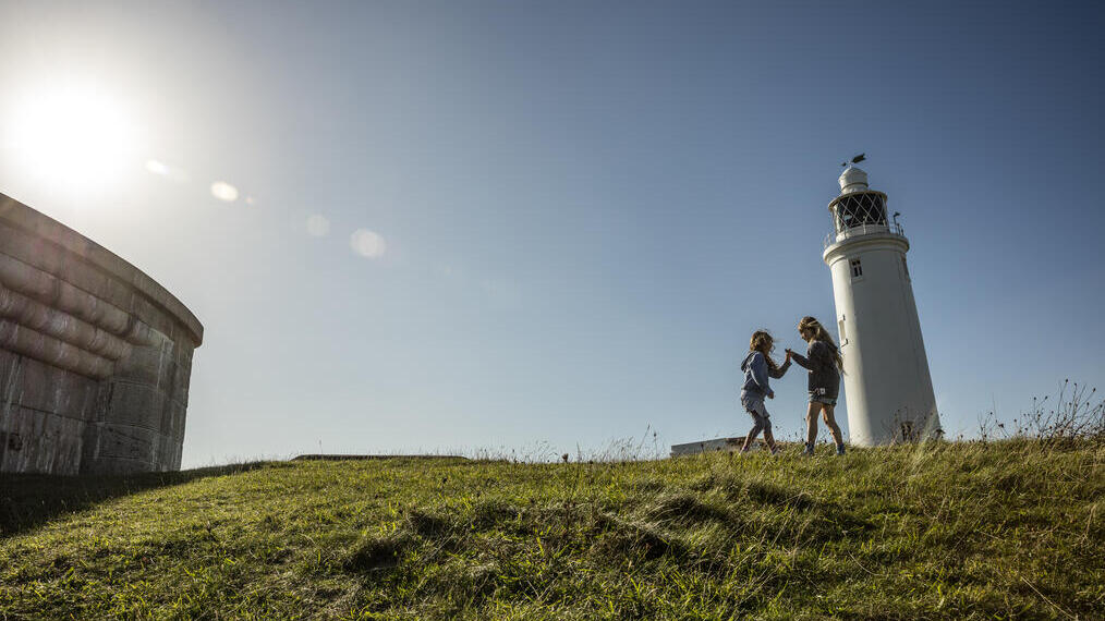 Dos niños jugando en un espacio abierto junto a un faro