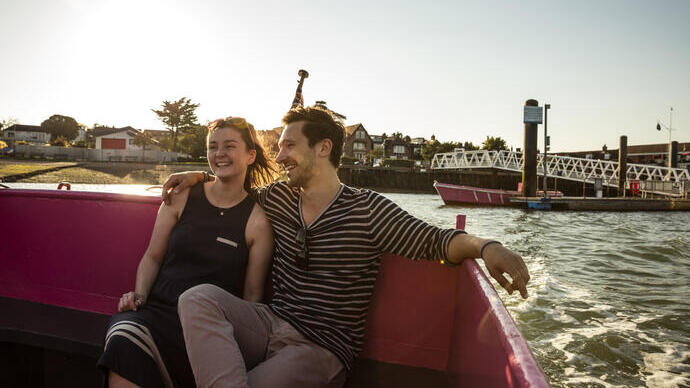 A couple seated on a bench on deck in evening sunshine