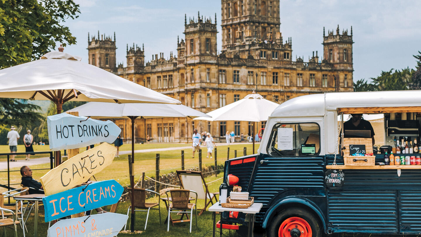 A food truck, parasols and direction signs in the ground of a castle