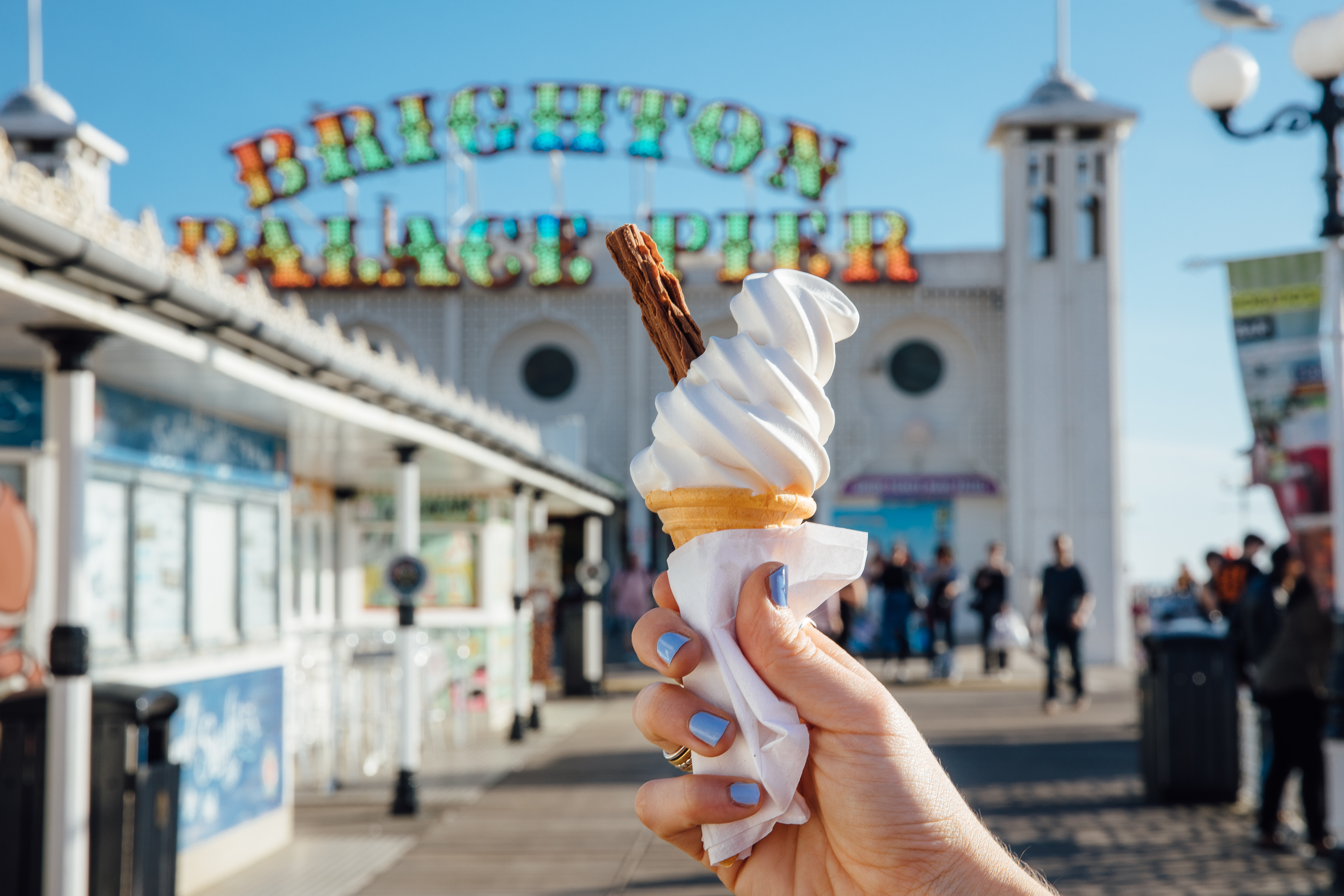 Close up of person holding ice cream cone on pier
