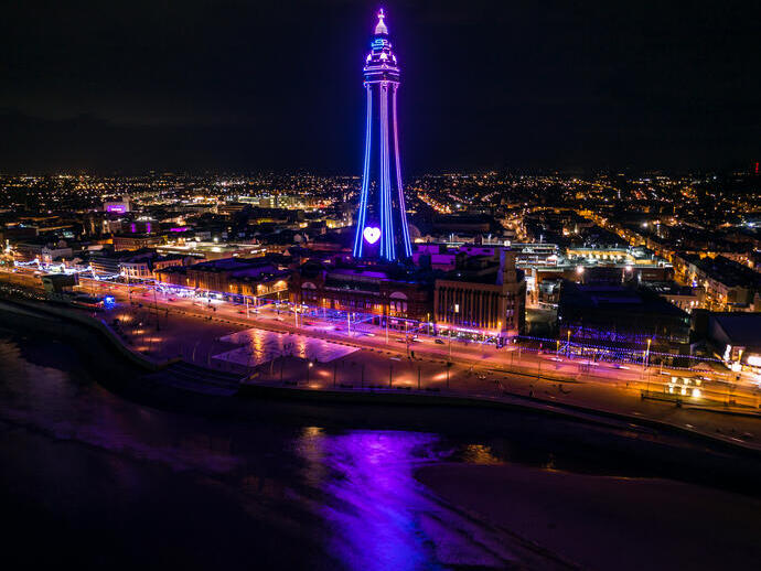 Seaside town at night with tower lit up.