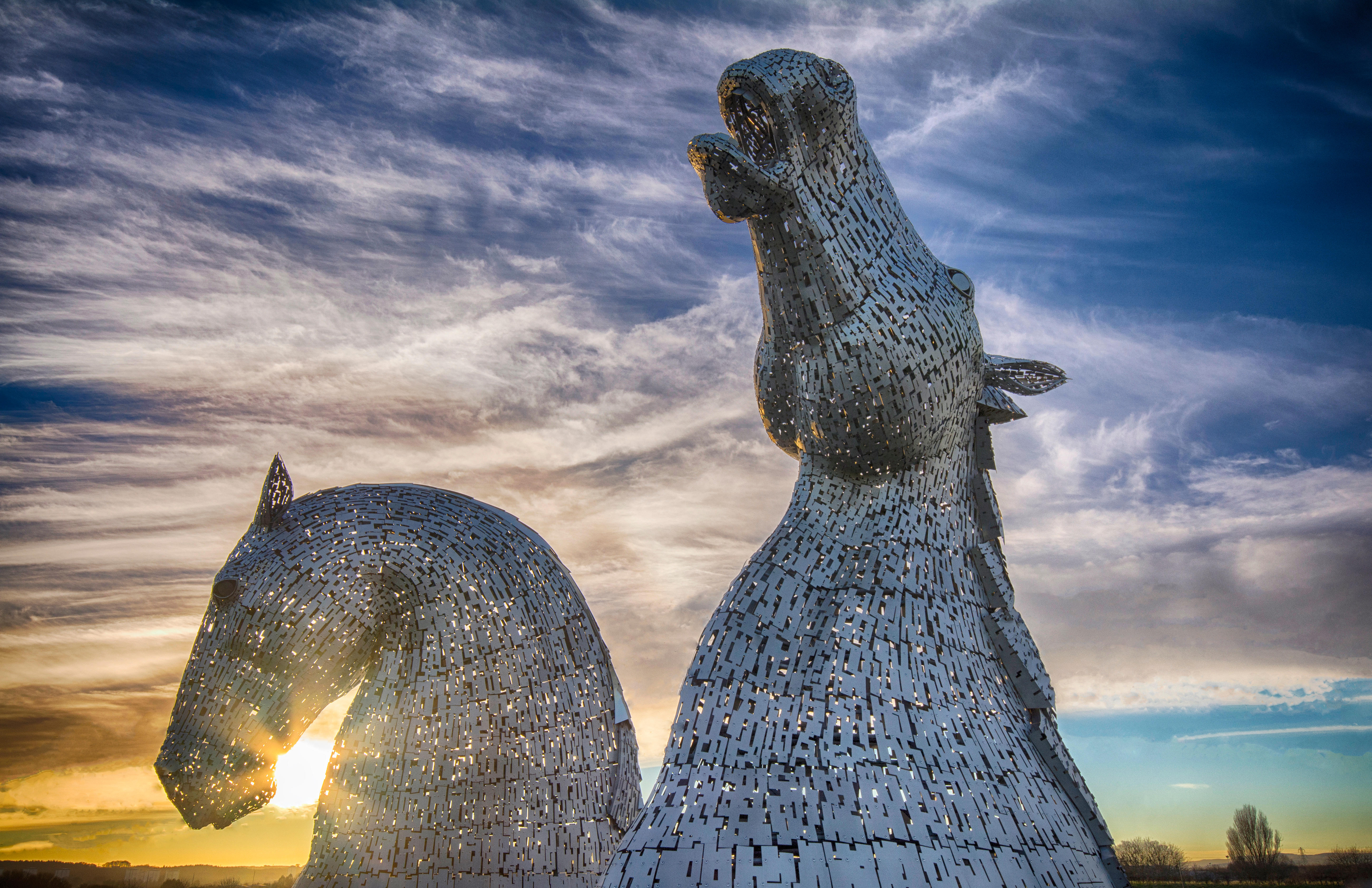 Pair of enormous horse head sculptures at sunset.