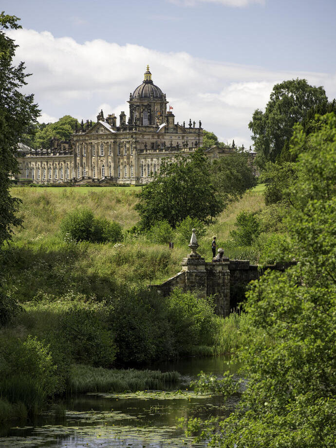 Großes Landhaus, umgeben von Bäumen, mit einem Bach im Vordergrund