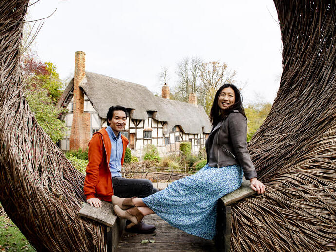 A young couple at Anne Hathaway's Cottage sitting on Tom Hare's 'The Moon Seat', Stratford-upon-Avon, Warwickshire, England