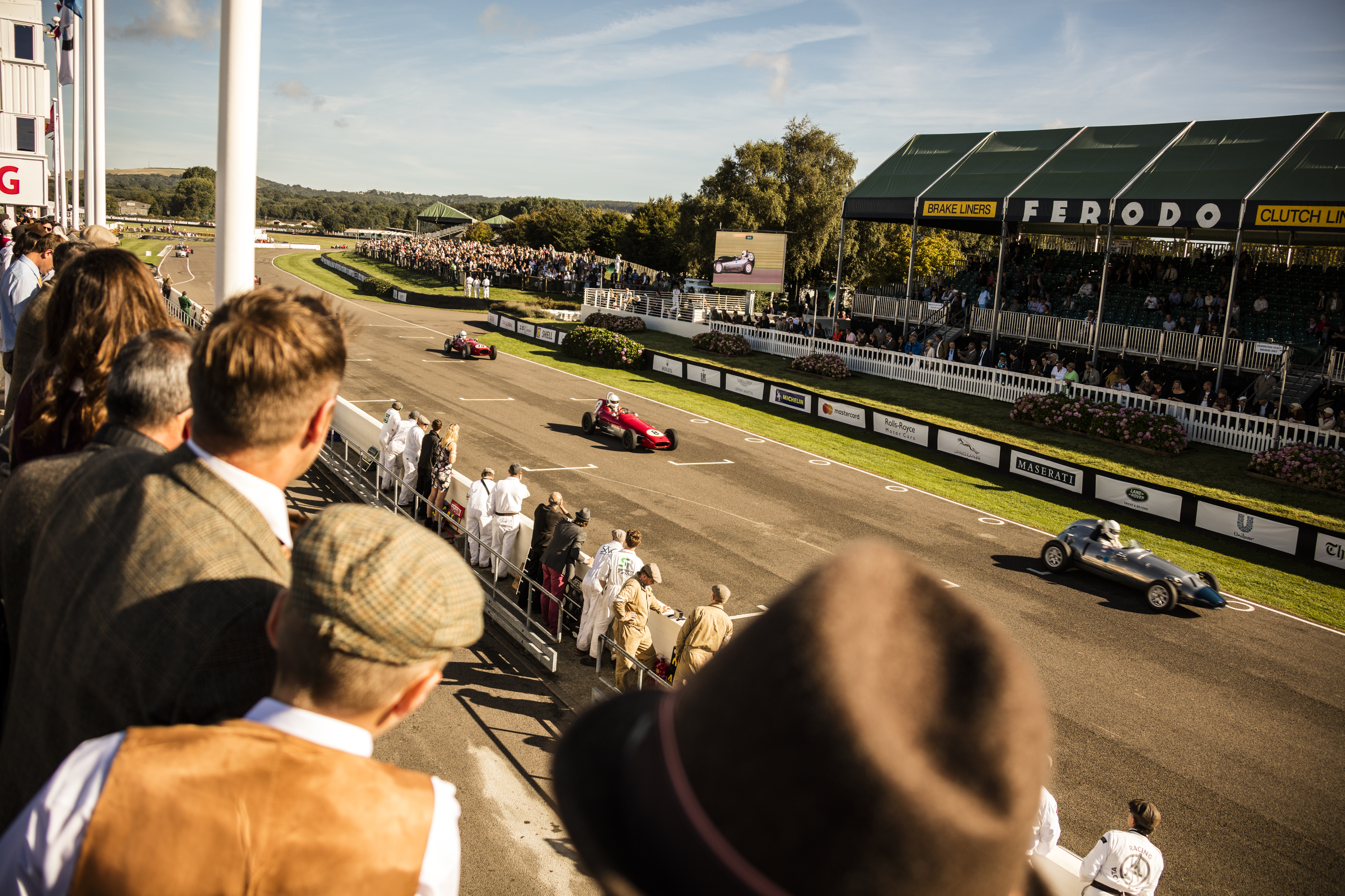 People in a grandstand watching a vintage sports car race