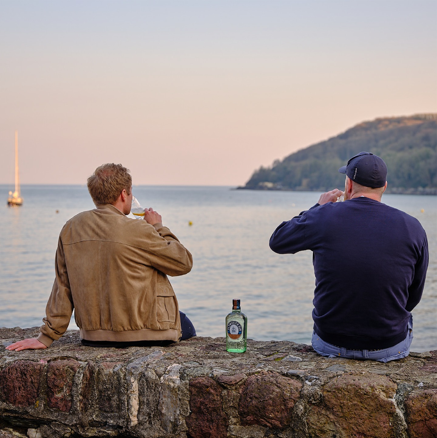 Dos hombres bebiendo ginebra mientras contemplan el mar