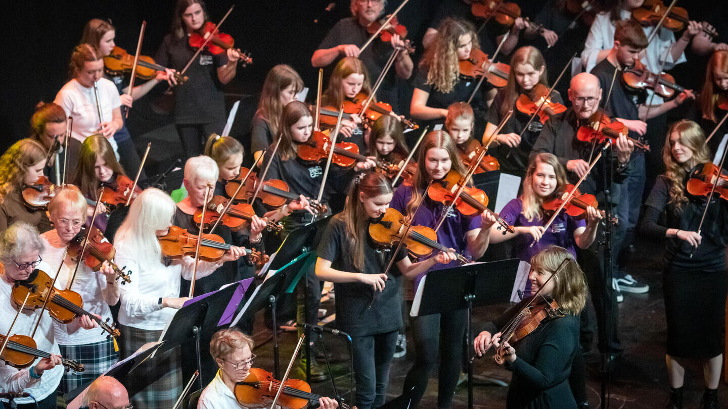 Patsy Reid si esibisce sul palco con i violinisti al concerto Our Language, Our Music alla Perth Concert Hall