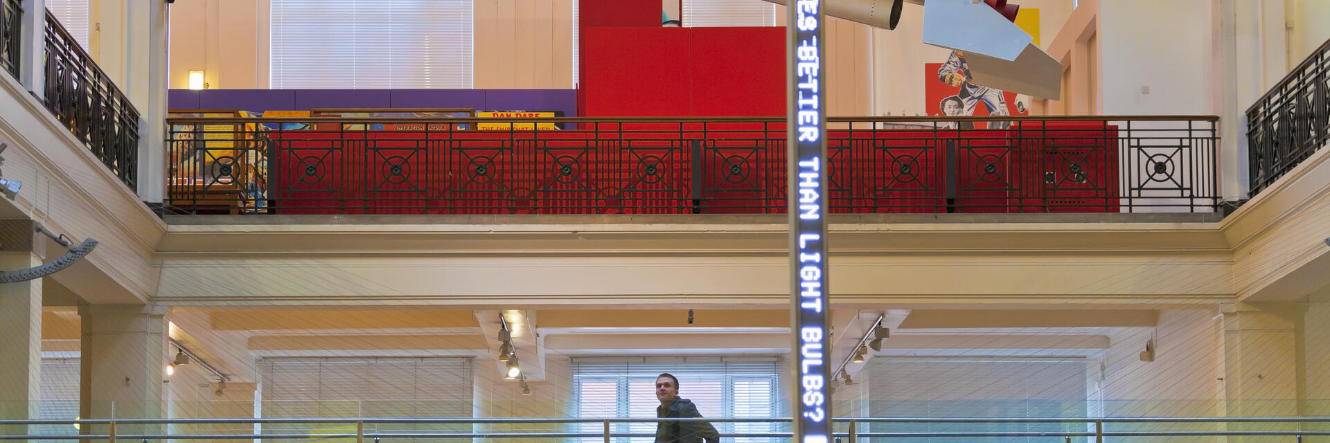 Hombre en silla de ruedas en una pasarela elevada de un museo contemplando la exposición