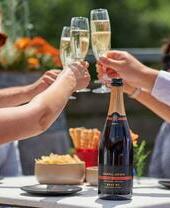 A group of people sat at a table toasting at Chapel Down Winery