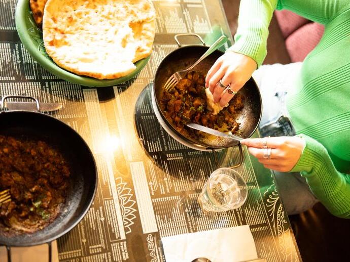 A curry dish and naan bread on the side served at a restaurant